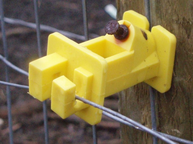This is a cheap plastic fence insulator meant for nailing to a wooden fencepost. I didn't take this picture, I found it somewhere but it's about what I've got. Note; most insulators are meant for metal posts instead of wood. Buy the right kind.